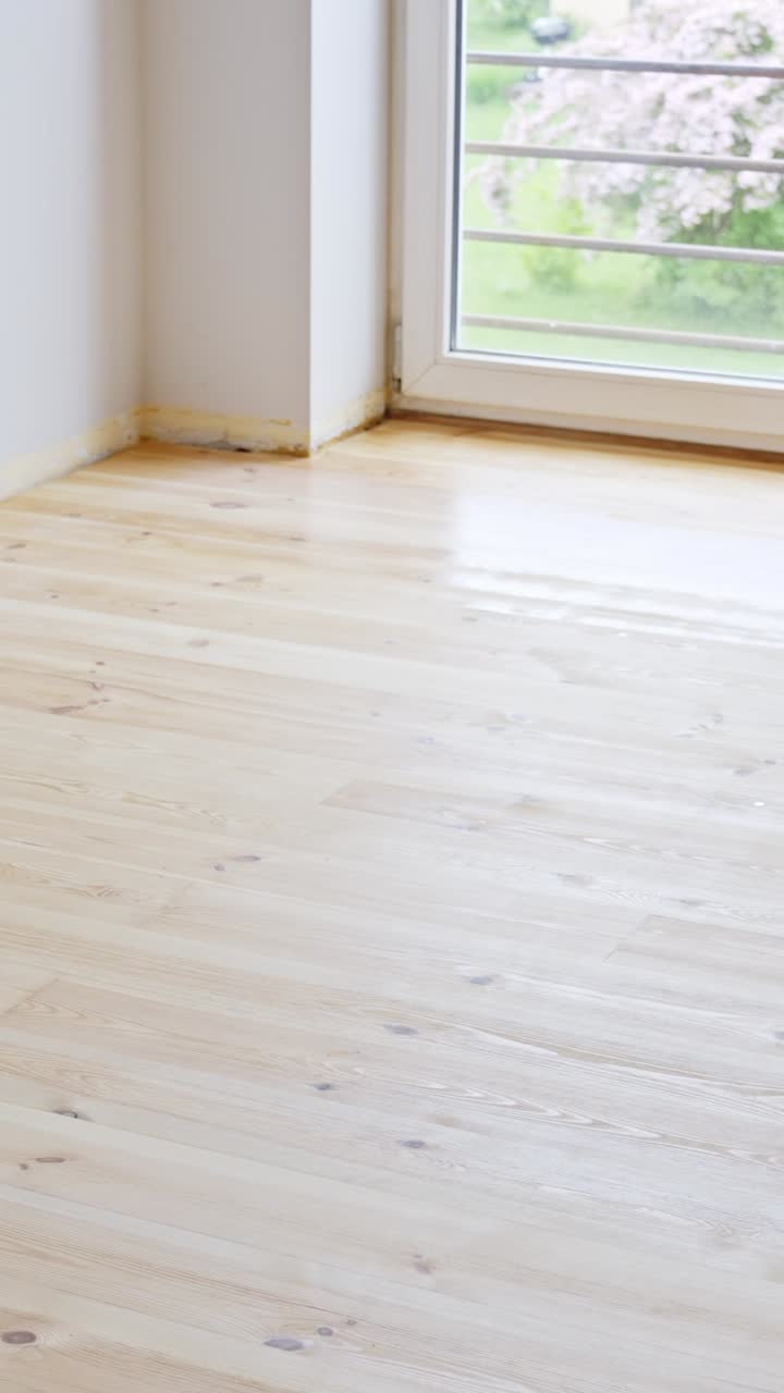 Close-up of hardwood floor coating with a roller during a DIY home renovation