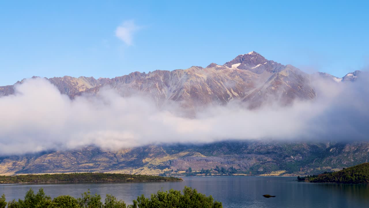 Fog drifts over Glenorchy mountains and Lake Wakatipu, revealing stunning peaks under clear blue skies