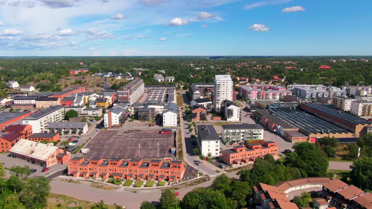 Bred flygbild över Gustavsbergs stad med färgglada byggnader och en grönskande park