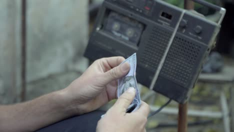 homeless counts the dollars, on the background of vintage tape recorder 4k