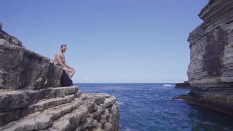 man sitting on cliffs by the sea.