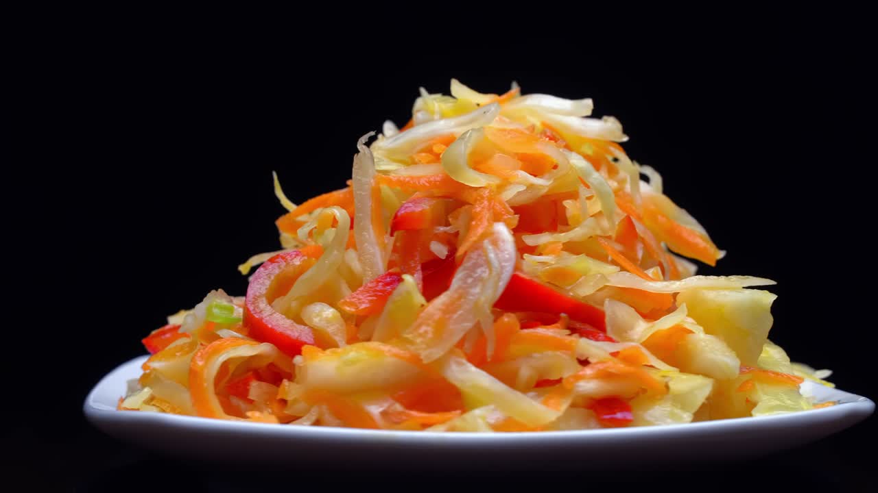 ensalada de verduras frescas en un plato blanco gira sobre un fondo negro.