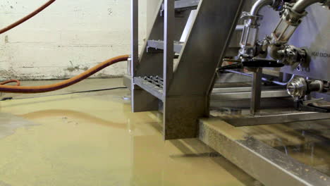 residuos de cerveza líquido que se escapa del grifo en el suelo en la fábrica de cerveza industrial