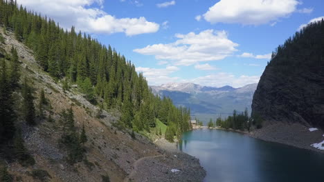 Aerial-descends-to-beautiful-Agnes-Lake-Teahouse,-Banff-National-Park