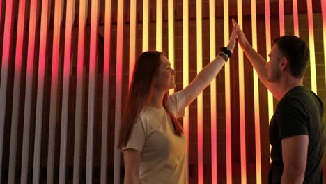 Slow Motion Video of two Young People in Love Holding Hands while Standing against a Colored Light Slow Motion Video of two Young People in Love Holding Hands while Standing against the Background of a Colorful Wall Beautiful People in Love on the Background of Light Effects
