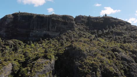 Drone-Aéreo-Volando-Hacia-Arriba-Hacia-El-Borde-De-Un-Enorme-Acantilado-De-Montaña,-Moviéndose-Sobre-Las-Rocas