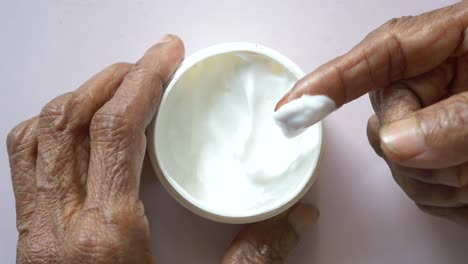 senior woman applying beauty cream onto skin