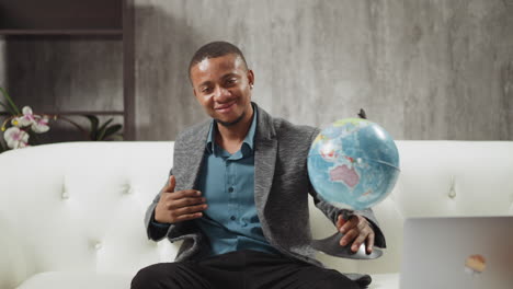 Geography teacher turns globe inviting students to lesson