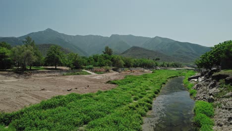 AERIAL---City,-river,-and-mountains,-Santiago,-Nuevo-León,-Mexico,-forward-pan-right