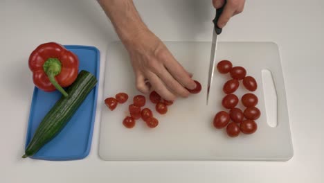 man cutting plum tomatoes with knife