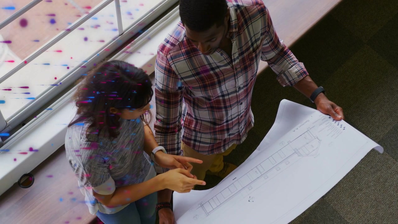 Woman and man pointing then leaning, initiating design blueprint review beside window speckles