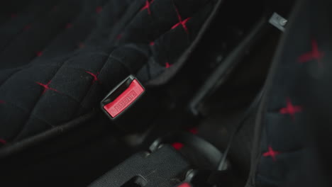 hand view of motorist adjusting seat belt strap over shoulder inside car cabin intimate focus on hand movement securing latch and buckle for safety before cold urban commute drive