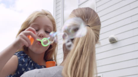 mother and daughter blowing bubbles in the yard happy family home