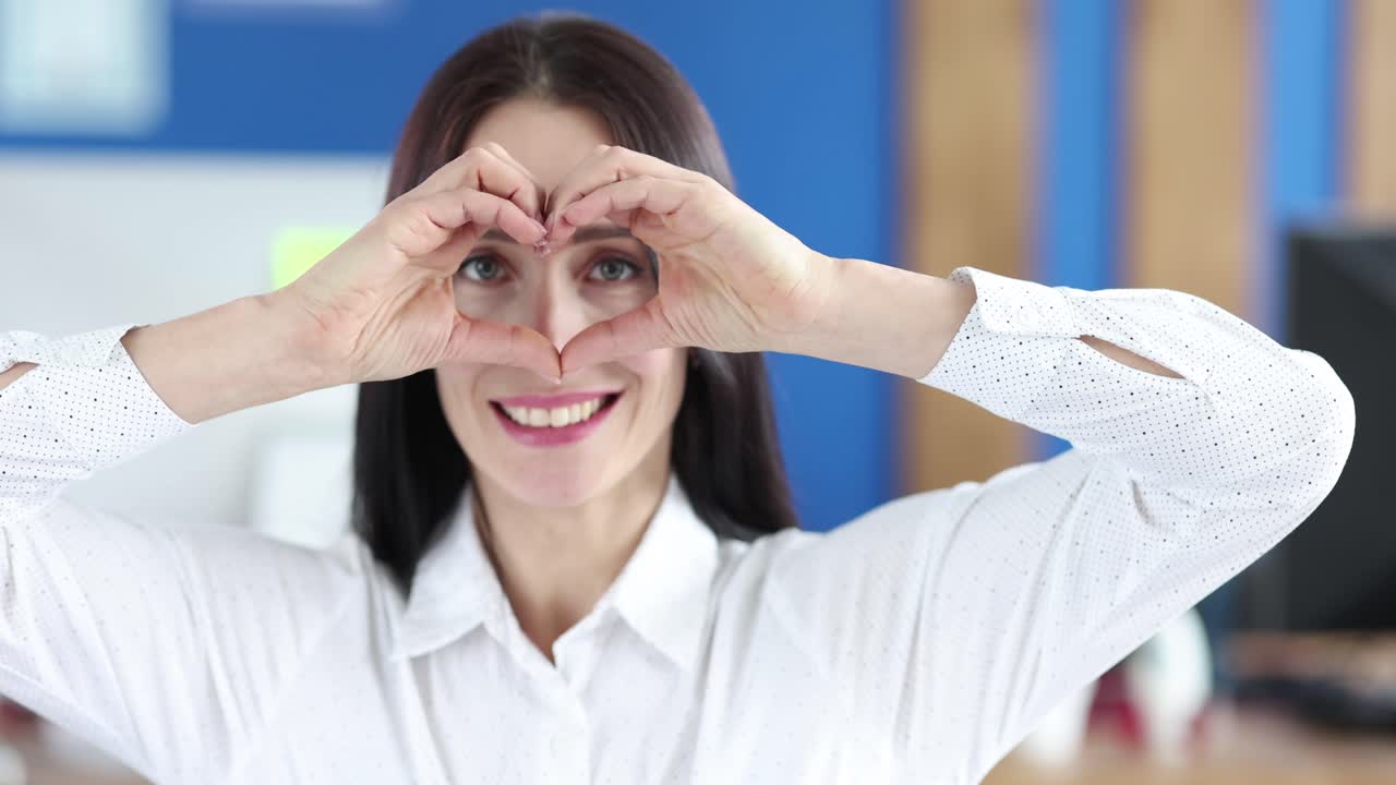 Retrato de mujer joven y feliz que hace un corazón con las manos