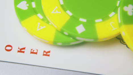 green casino chips and joker card on light grey surface