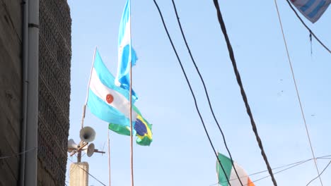 Low-angle-shot-of-Argentina-and-Brazil-flag-waving-in-the-wind-with-blue-sky-in-the-background