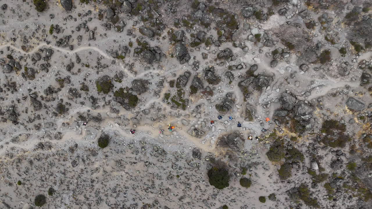 una toma aérea en ángulo descendente de personas caminando por un sendero de montaña, una toma épica de un dron.