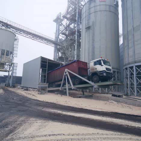 unloading crops from a lorry to grain storage. lorry standing on a special platform to ease the process of unloading. loaded truck at the backdrop of elevator factory