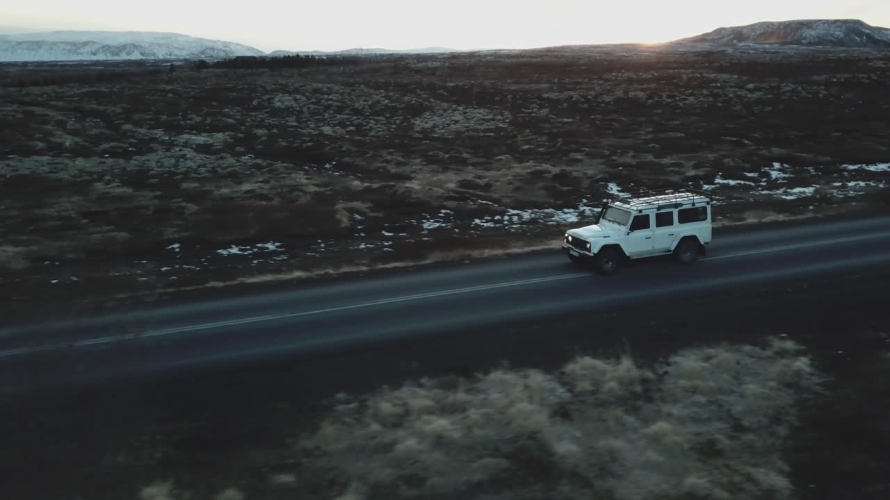 Soğuk İzlanda'da boş bir caddede ilerleyen Land Rover'ın havadan görünümü.