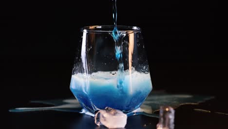 la bebida azul se desborda de un vaso con hielo