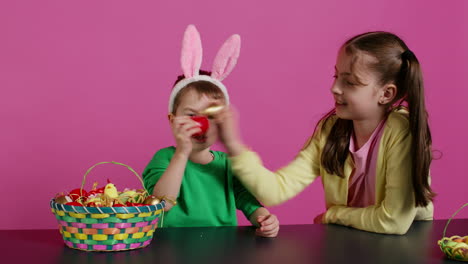 sweet children knocking eggs together for easter tradition in studio,