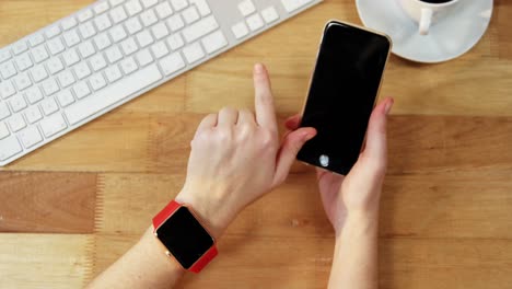 Hand-of-businesswoman-using-mobile-phone-at-desk