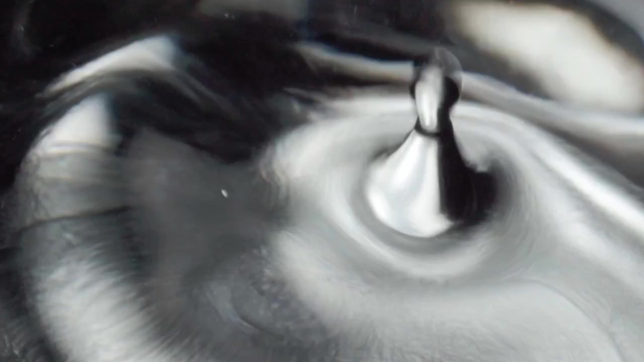 Closeup of metallic liquid surface forming abstract swirling patterns and ripple effect. Smooth fluid movement creating reflective texture with dynamic circular motion