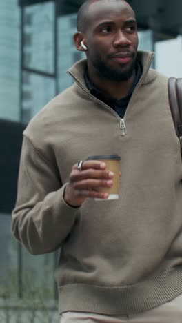 man walking and drinking coffee in city