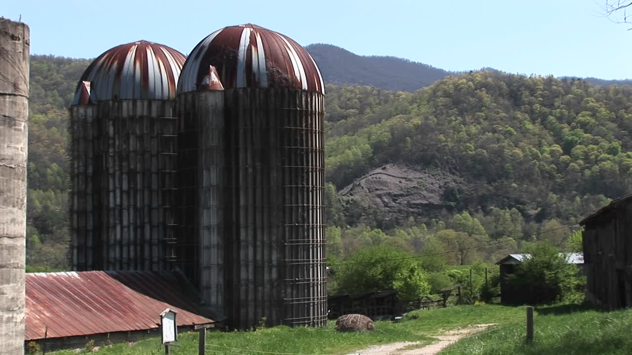 큰 곡물 사일로와 주변 산이 이 시골 농장의 풍경을 지배합니다.