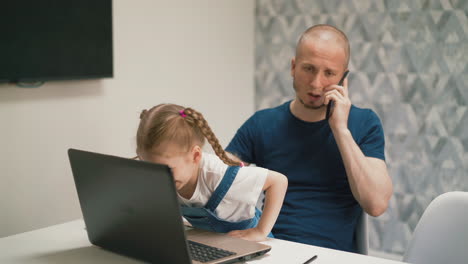 Papá-Habla-Por-Teléfono-Mientras-La-Niña-Usa-Video-Chat-En-La-Computadora