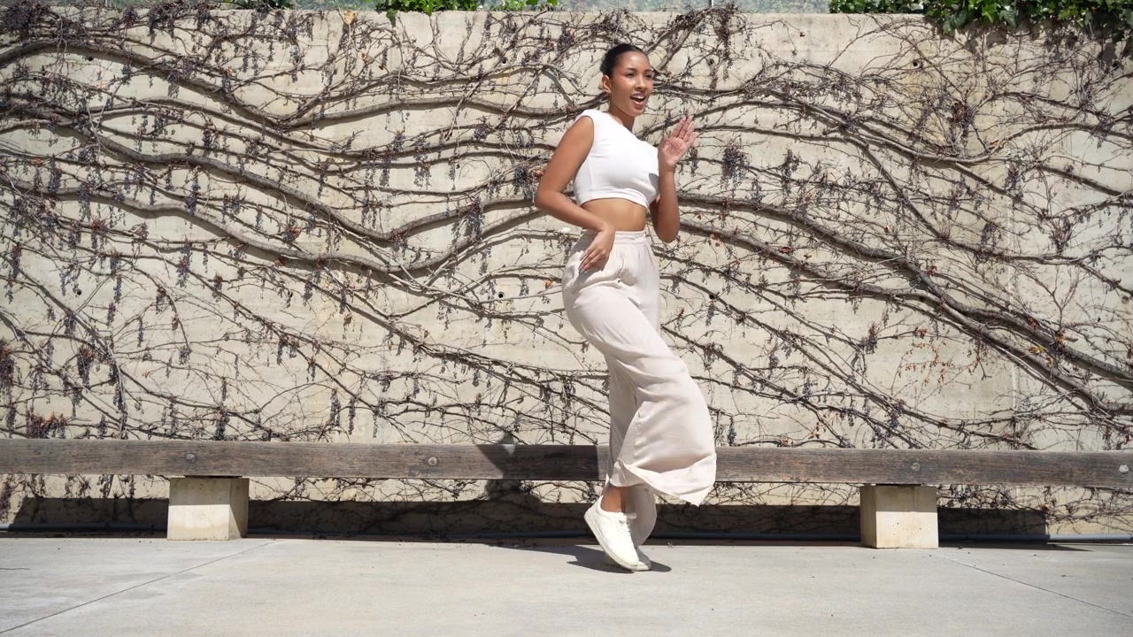 Una mujer con estilo posando elegantemente con confianza contra una pared artística y creativa.