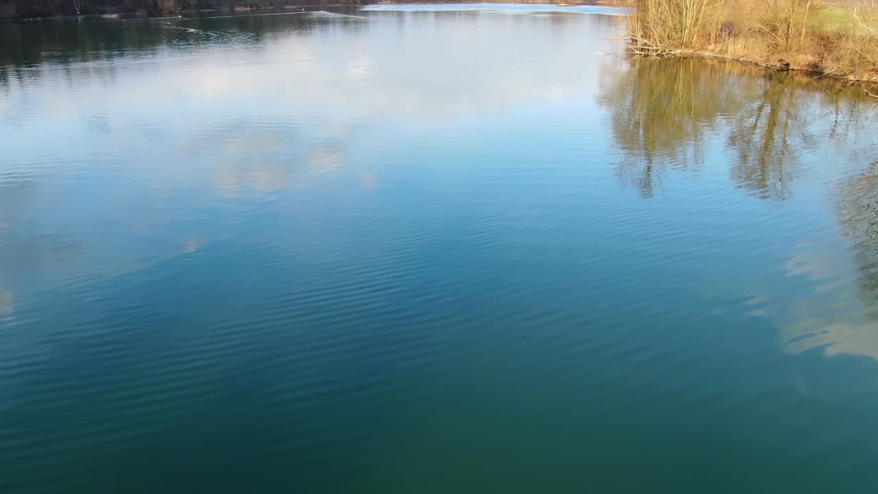 Ribnik Vrbje fishing lake in Slovenia with an observation deck with telescope, Aerial low flyover tilt up shot
