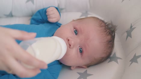 el niño pequeño come leche mezclada con la ayuda de la madre en un capullo suave