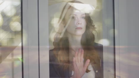 animación de manchas de luz sobre mujer caucásica mirando por la ventana.