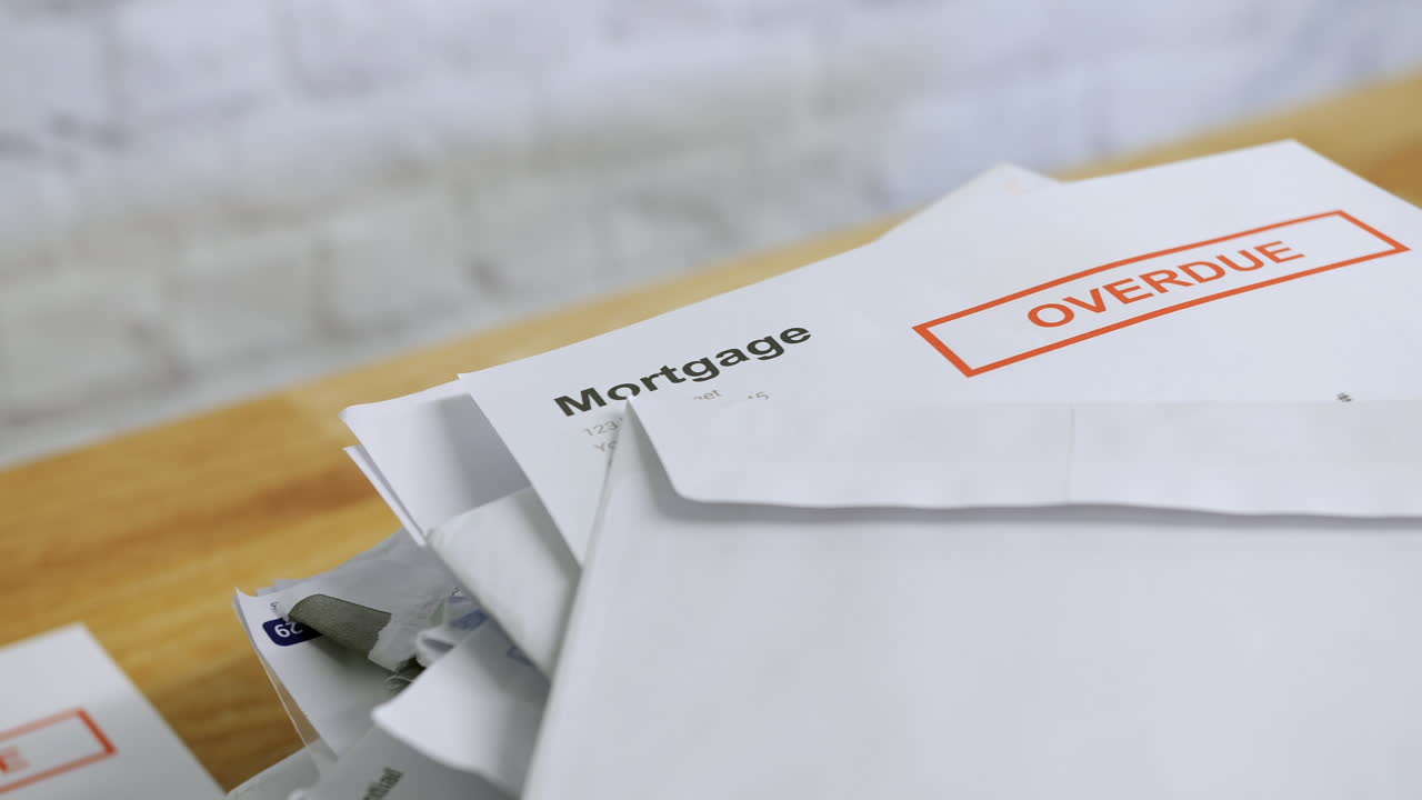 una pila de billetes y cartas con aviso de vencimiento de deudas hipotecarias