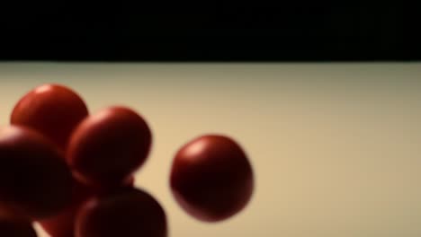 Slow-motion-footage-of-red-tomatoes-falling-and-rolling-on-table