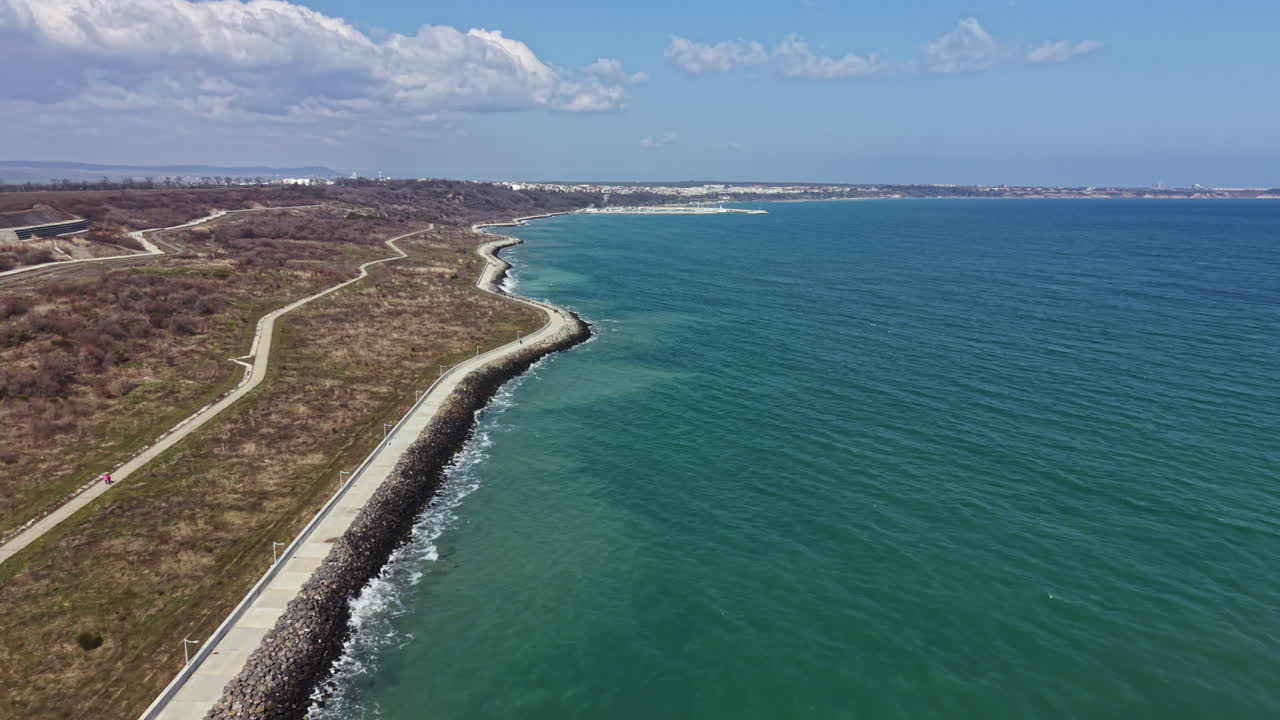 Splendida vista costiera con acqua cristallina e sentiero pedonale durante il giorno vicino a un'area urbana in riva al mare
