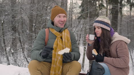 marido y mujer vestidos de invierno comiendo sándwiches y bebiendo té