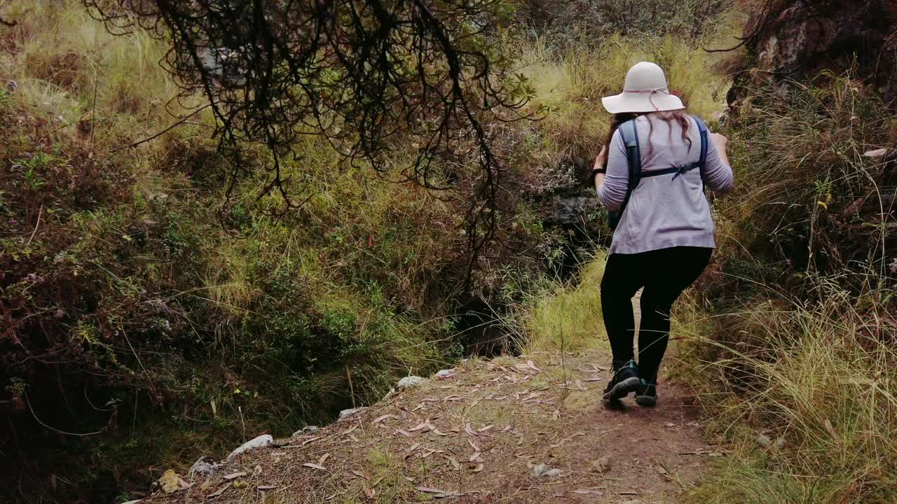 A hiker explores a scenic mountain trail near Cusco, following an ancient Inca path connecting Puka Pukara, Inkilltambo, and Rumiwasi ruins, part of the historic Qhapaq Ñan road network.