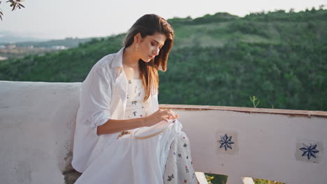 mujer inspirada haciendo bordados en la terraza con vista a la montaña. niña disfrutando de pasatiempo