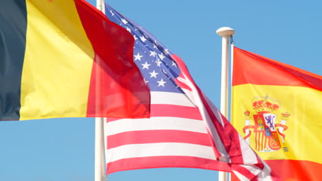 close up flags belgium, usa and spain waiving in the wind, sunny day