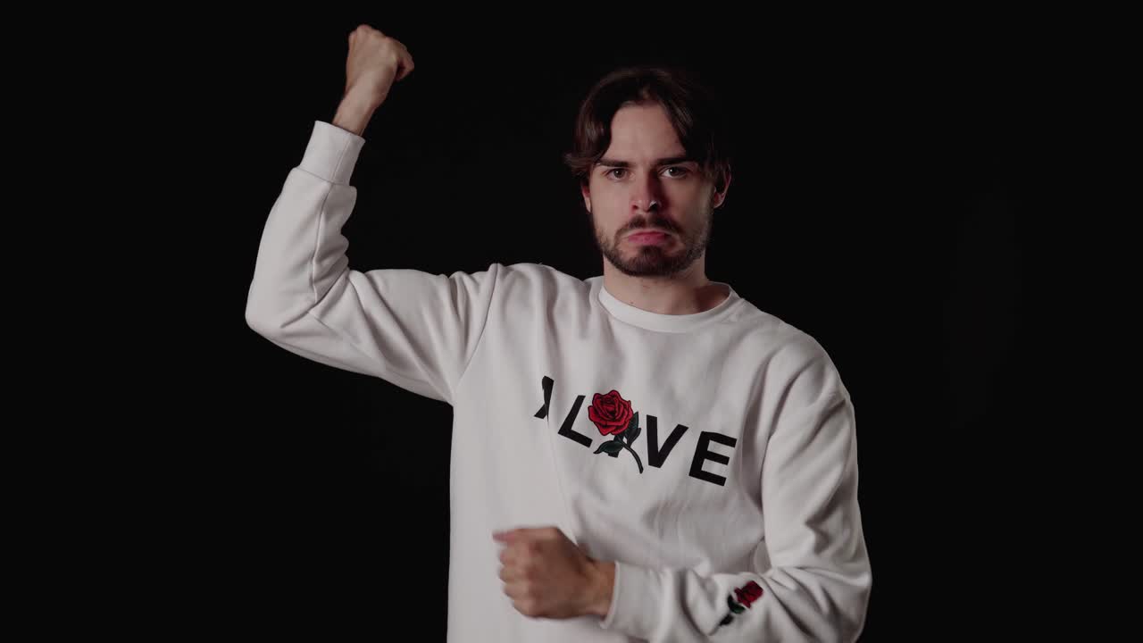 팔뚝을 구부리는 트렌디한 청년, 몸짓, 근육, 넓고 검은 배경을 과시하다