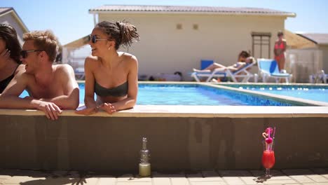 young attractive people hanging out at the side of the pool in the summertime 2