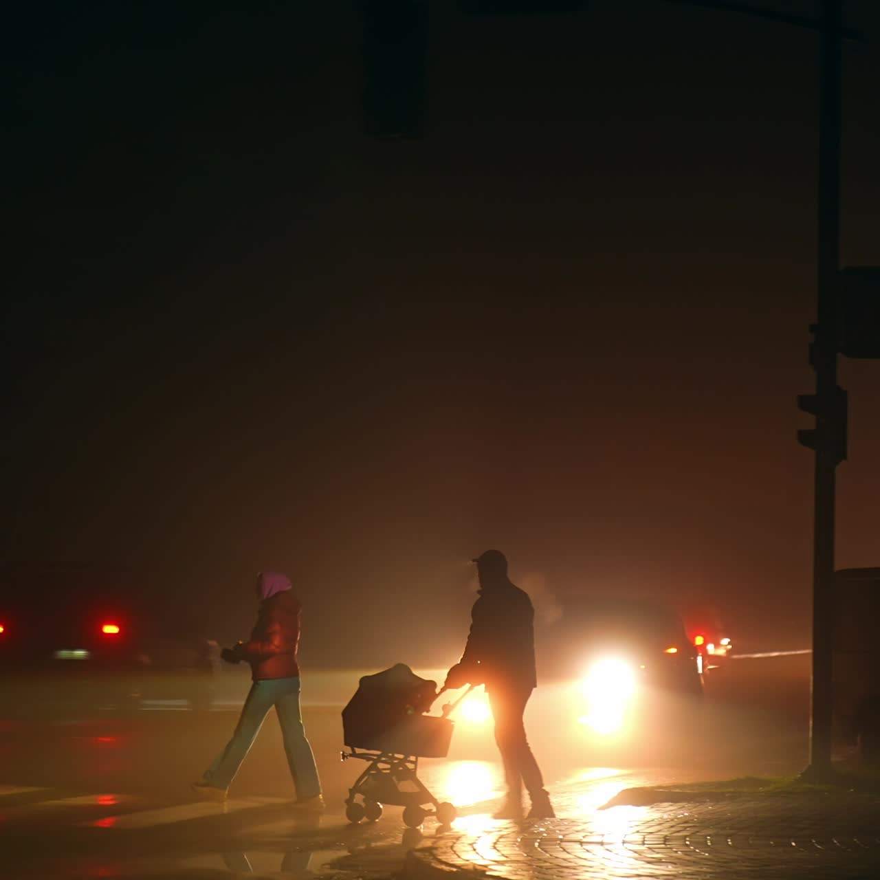 Family with a baby pram cross the road in blackout time. City covered with darkness during the electricity outage