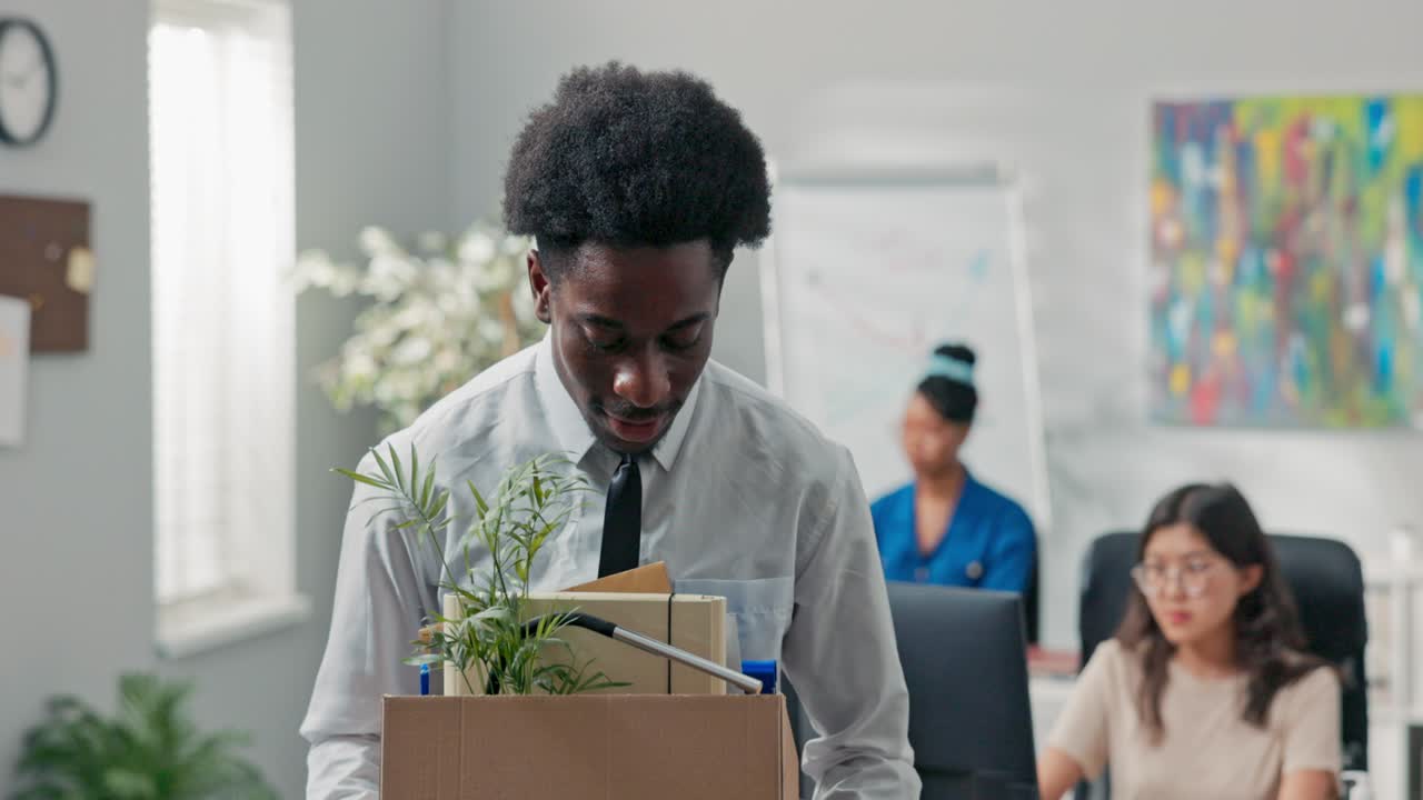 Man with afro hair quits company job walks out of office with things packed in box leaves corporation quits responsibilities retires leaves social room