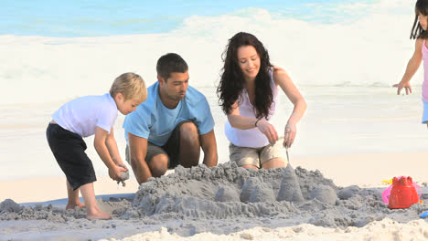 parents building a sand castle with their children