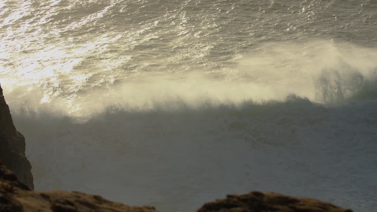 nazare에서 큰 파도가 부서지는 황금빛 일몰
