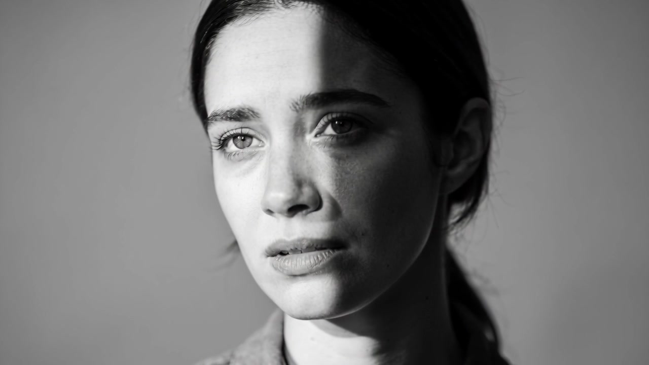 Shifting studio light causing woman turning head at studio, seeming sad with collared shirt