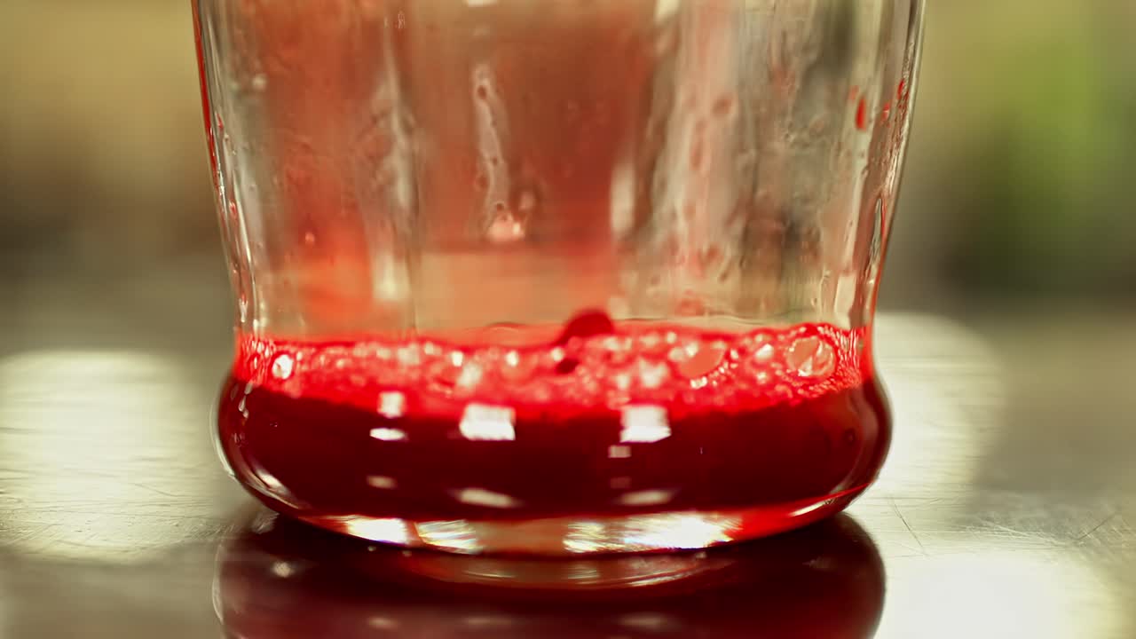 Pouring dense red liquid drink kombucha fermented tea dense air bubbles up-close