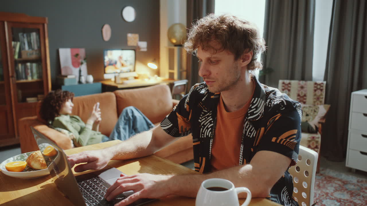 Freelancer Working Online on Laptop at Table in Living Room